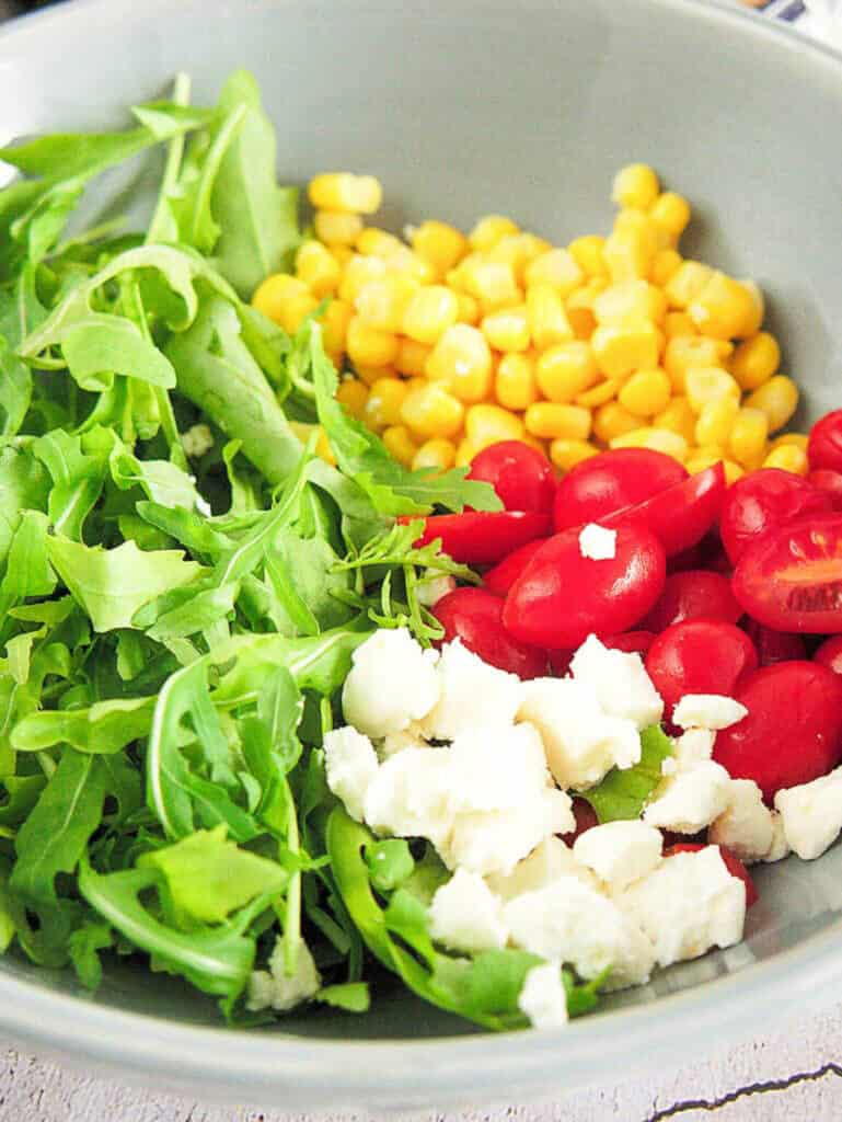 ingredients for arugula corn salad: corn, cherry tomatoes, goat cheese