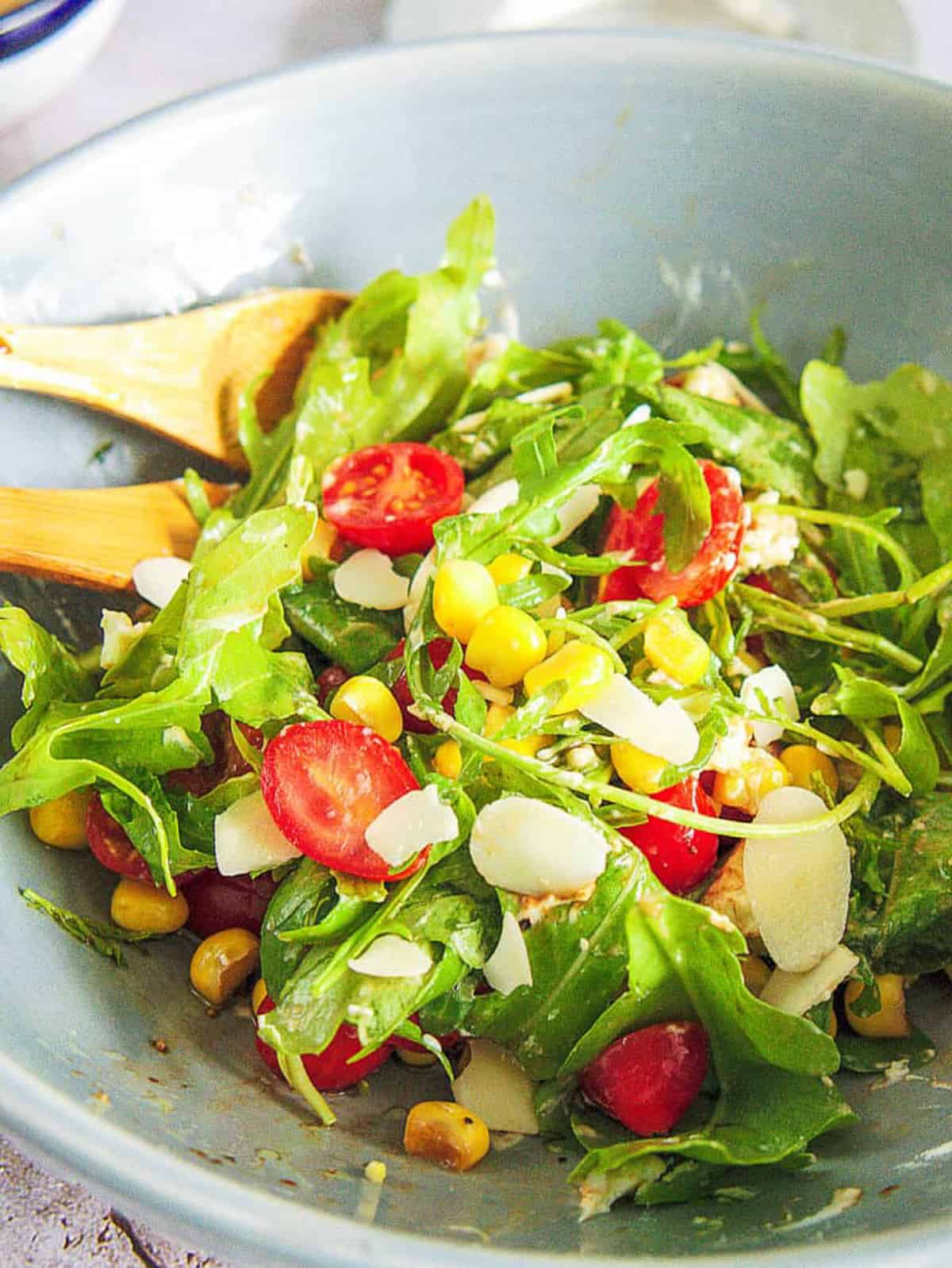 spinach and arugula salad with Tomatoes and Goat Cheese served in a light blue salad bowl