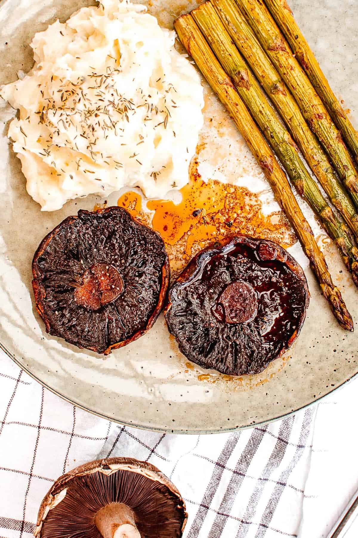 portobello mushroom steaks paired with mashed potatoes and asparagus served on a white plate