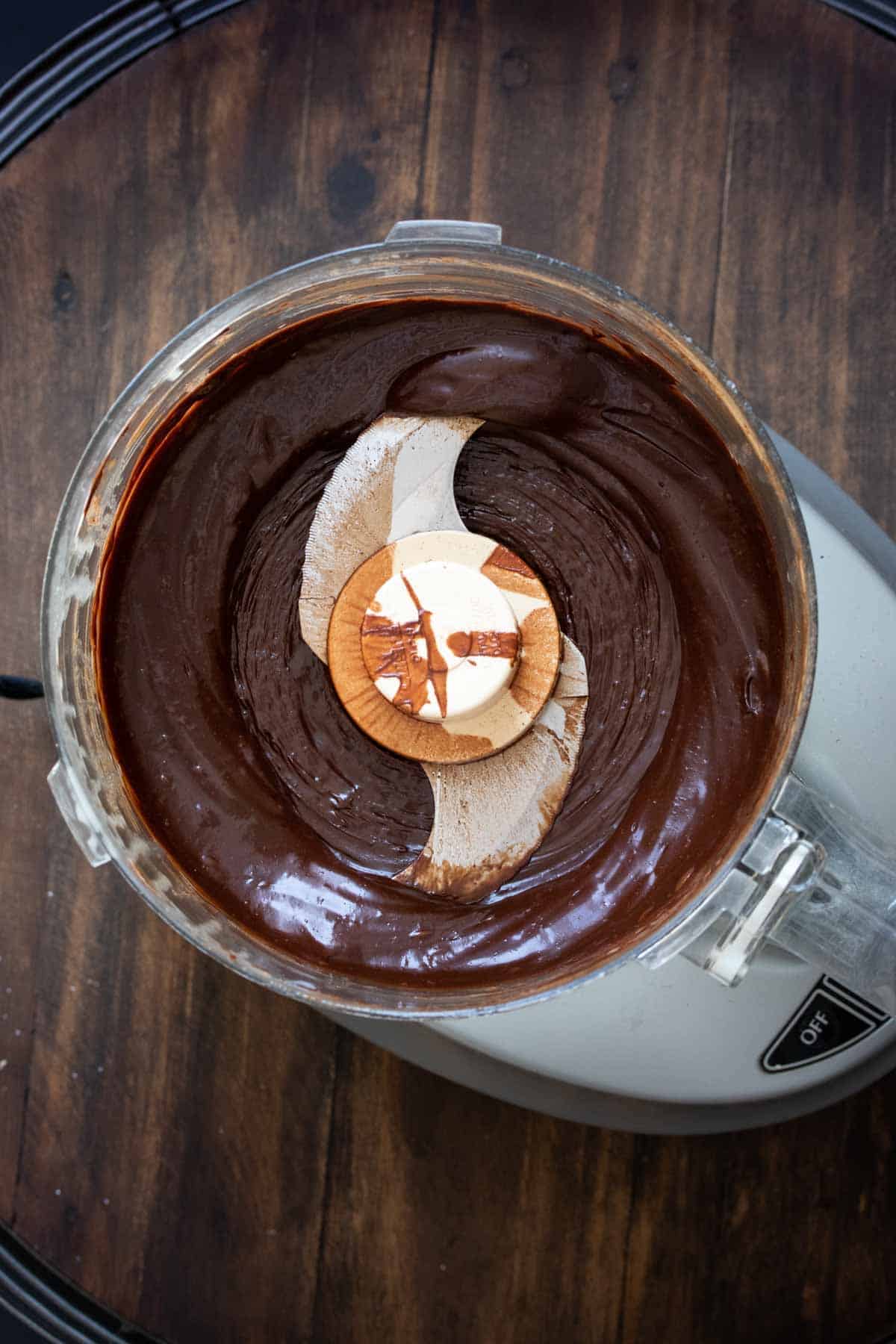 Top view of a food processor with smooth chocolate truffle mixture.