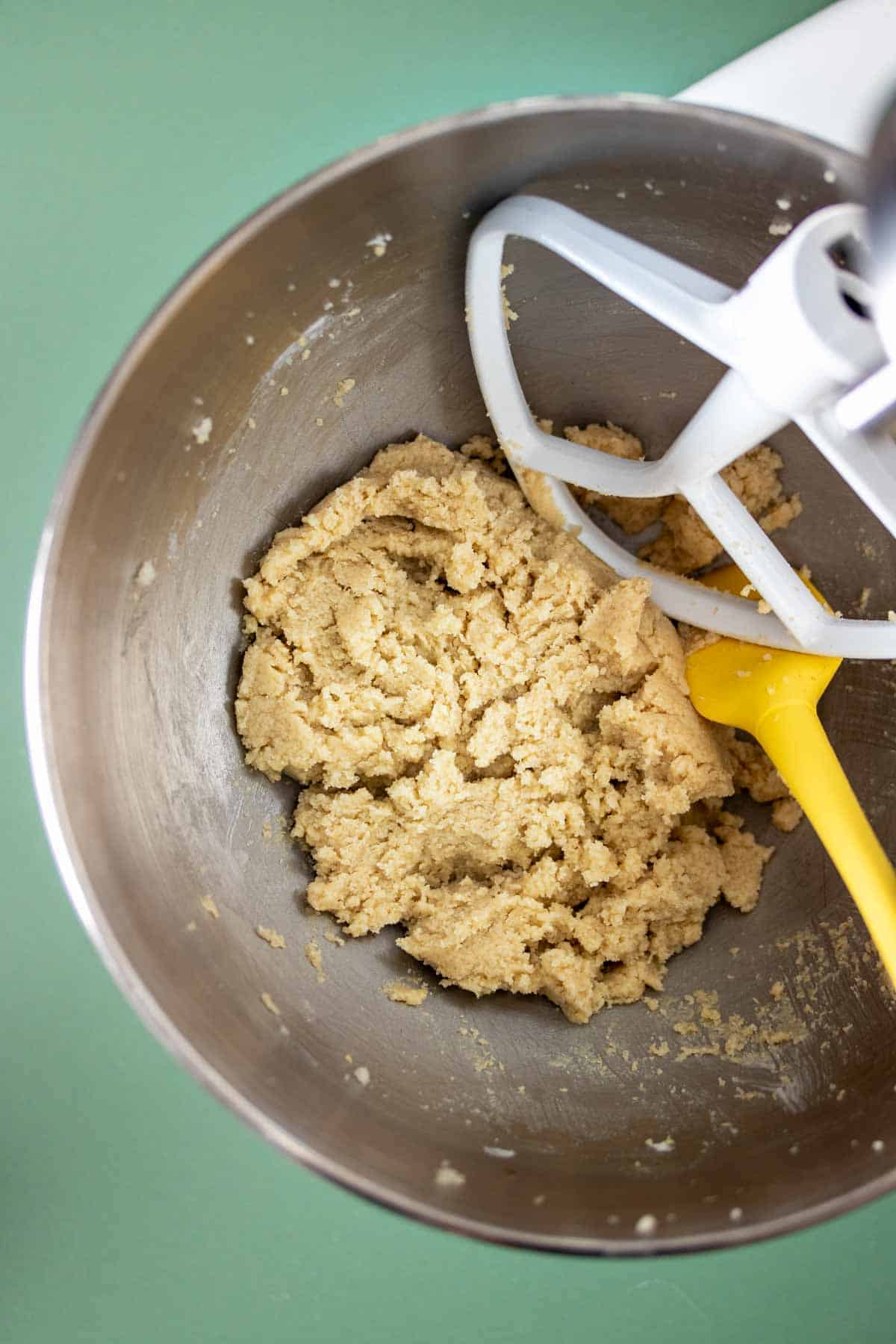 Top view of a silver bowl from a stand mixer with sugar cookie dough inside.