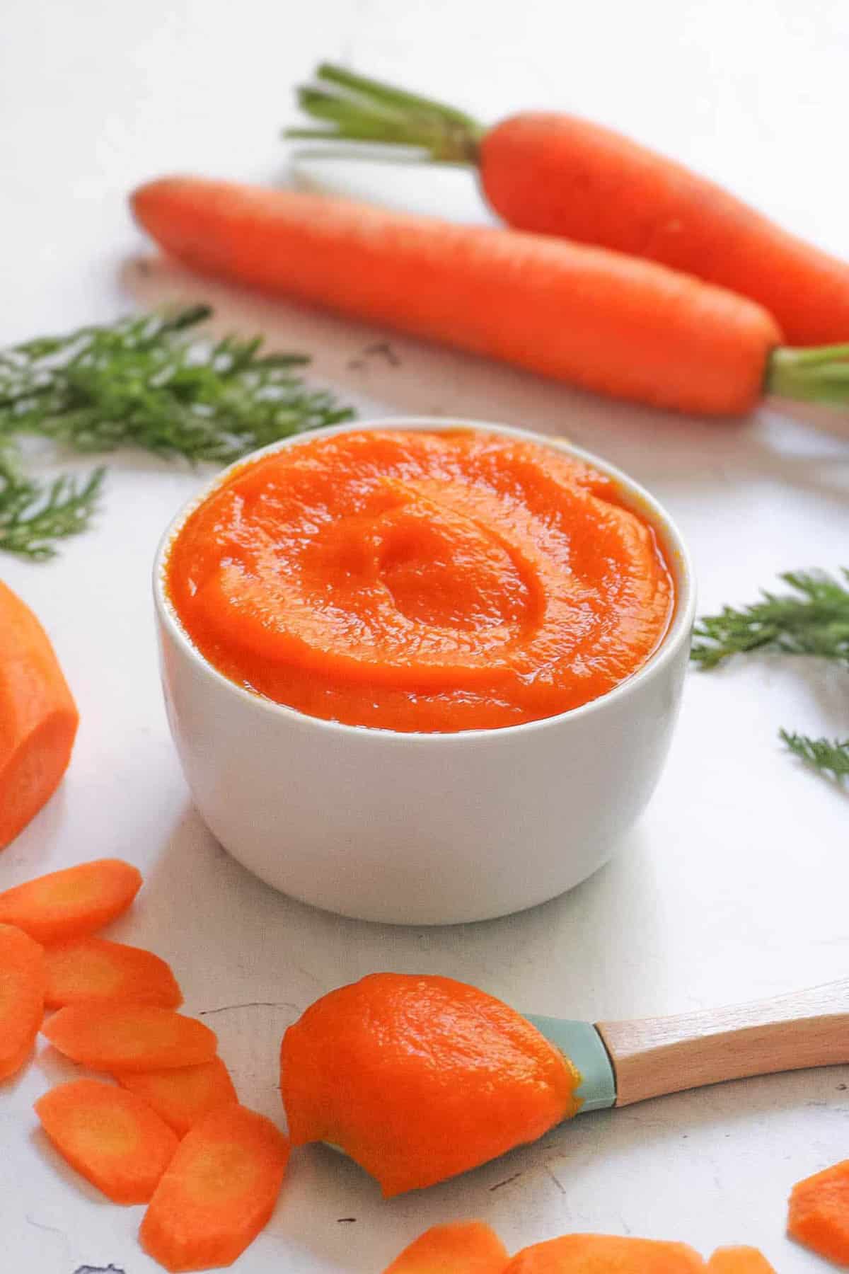 How to make carrot puree for baby: carrot baby food served in a white bowl.