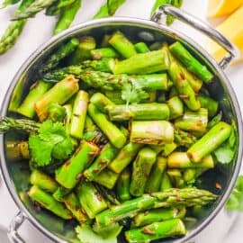 Indian asparagus stir fry served in a stainless steel bowl on a white countertop.