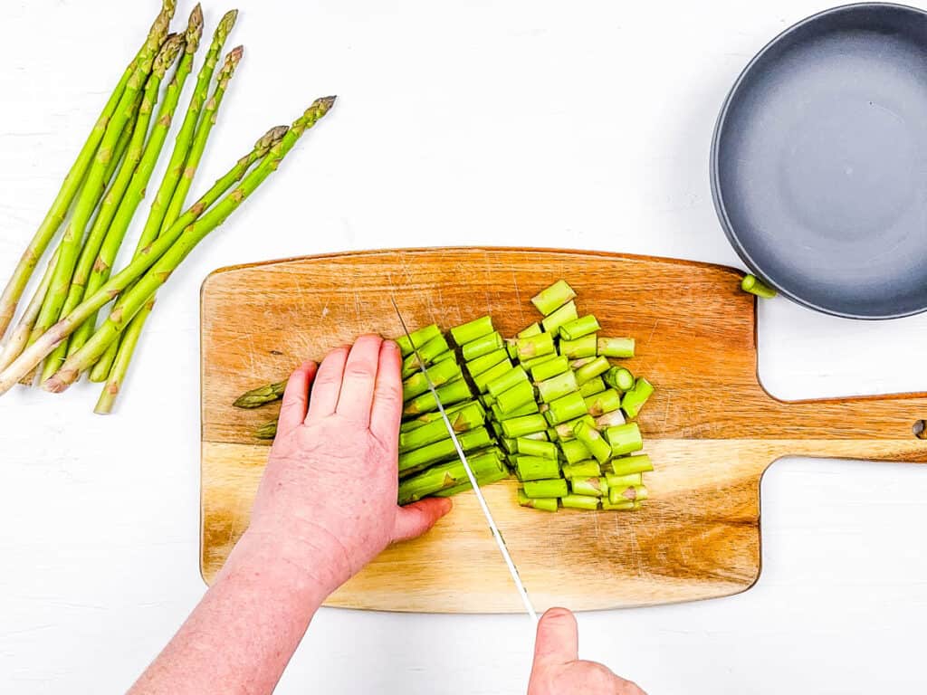 Fresh asparagus chopped on a cutting board.