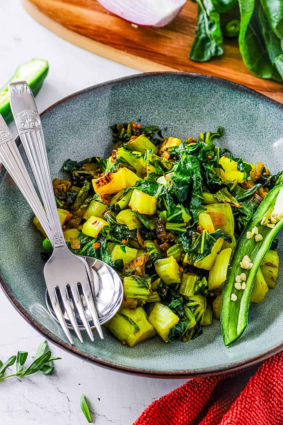 Indian bok choy served in a grey bowl with w fork and spoon on the side.