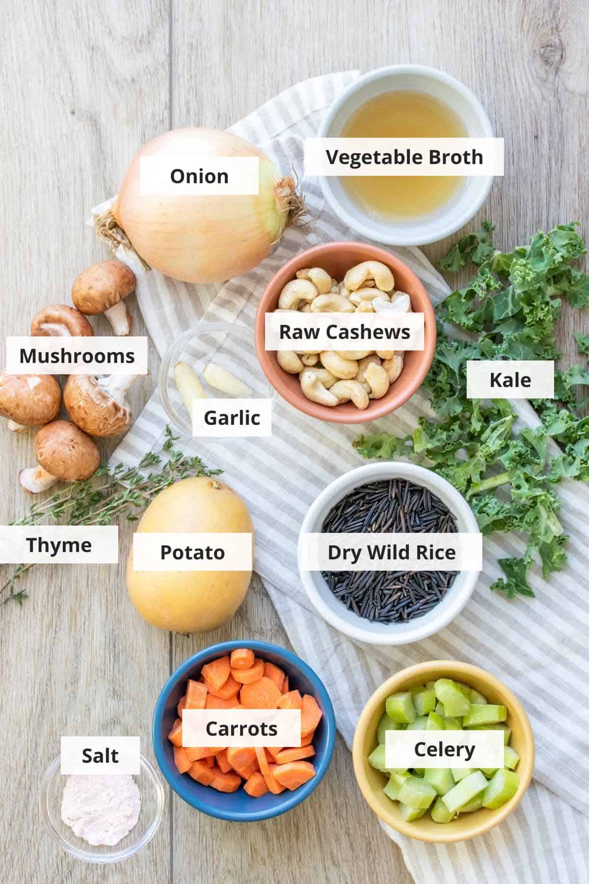 Ingredients for creamy veggie rice soup recipe on a light wood countertop.
