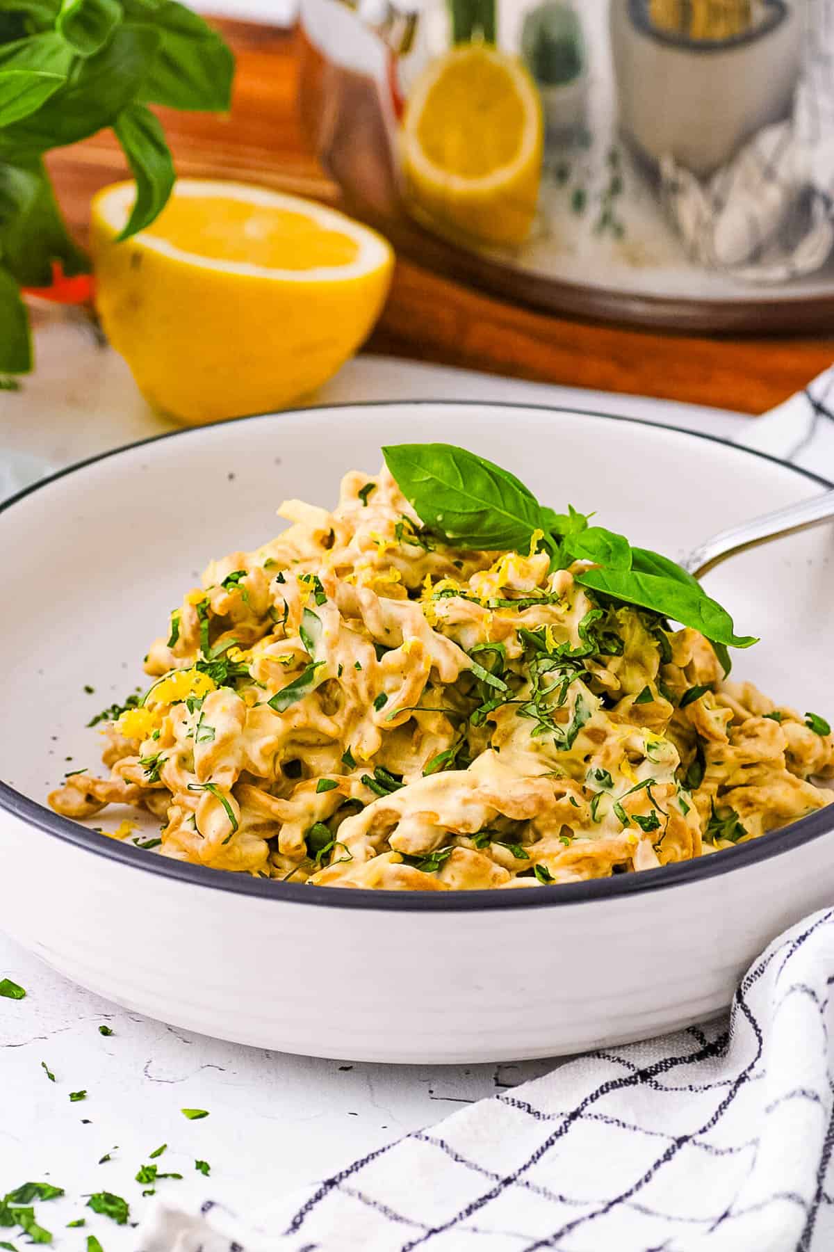 Tahini pasta, served in a white bowl, garnished with fresh herbs.