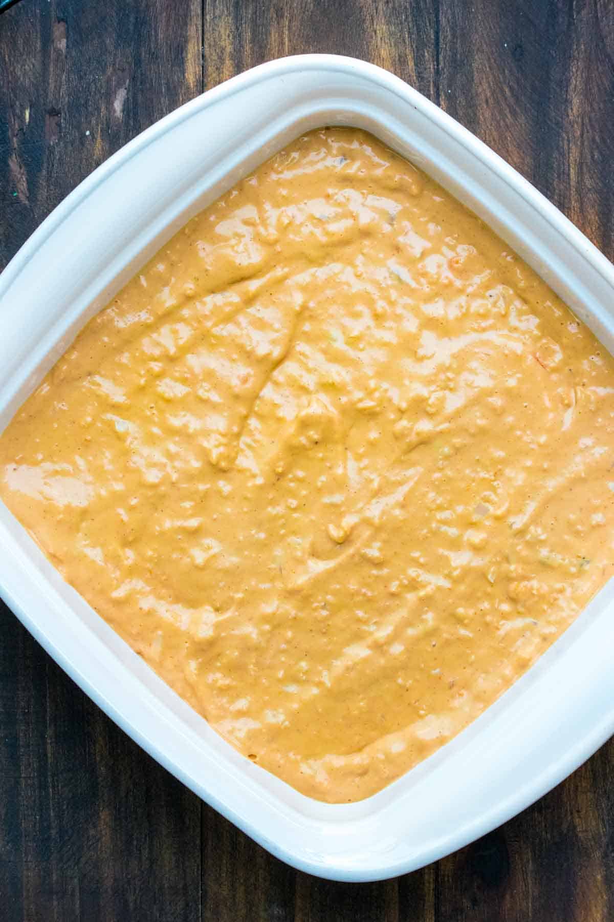 Top view of a white square baking dish with buffalo chicken dip inside that hasn't been baked yet.