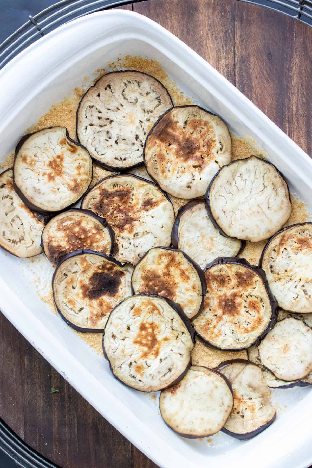 A white baking dish with round slices of eggplant layered on each other.