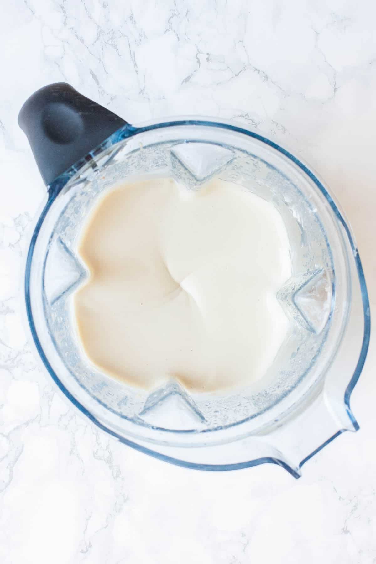 Top view of a blender with a white creamy sauce inside.