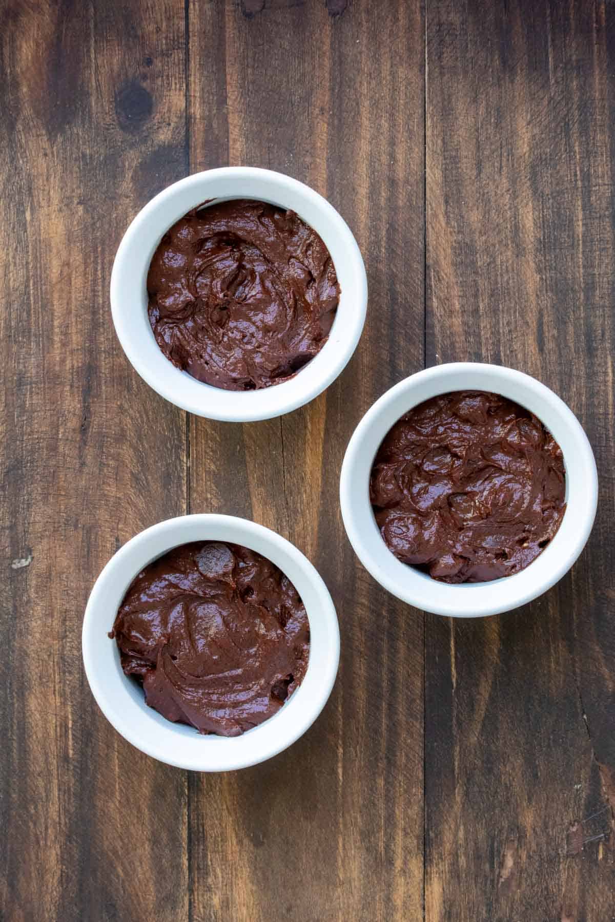 Three white ramekins filled with chocolate batter.