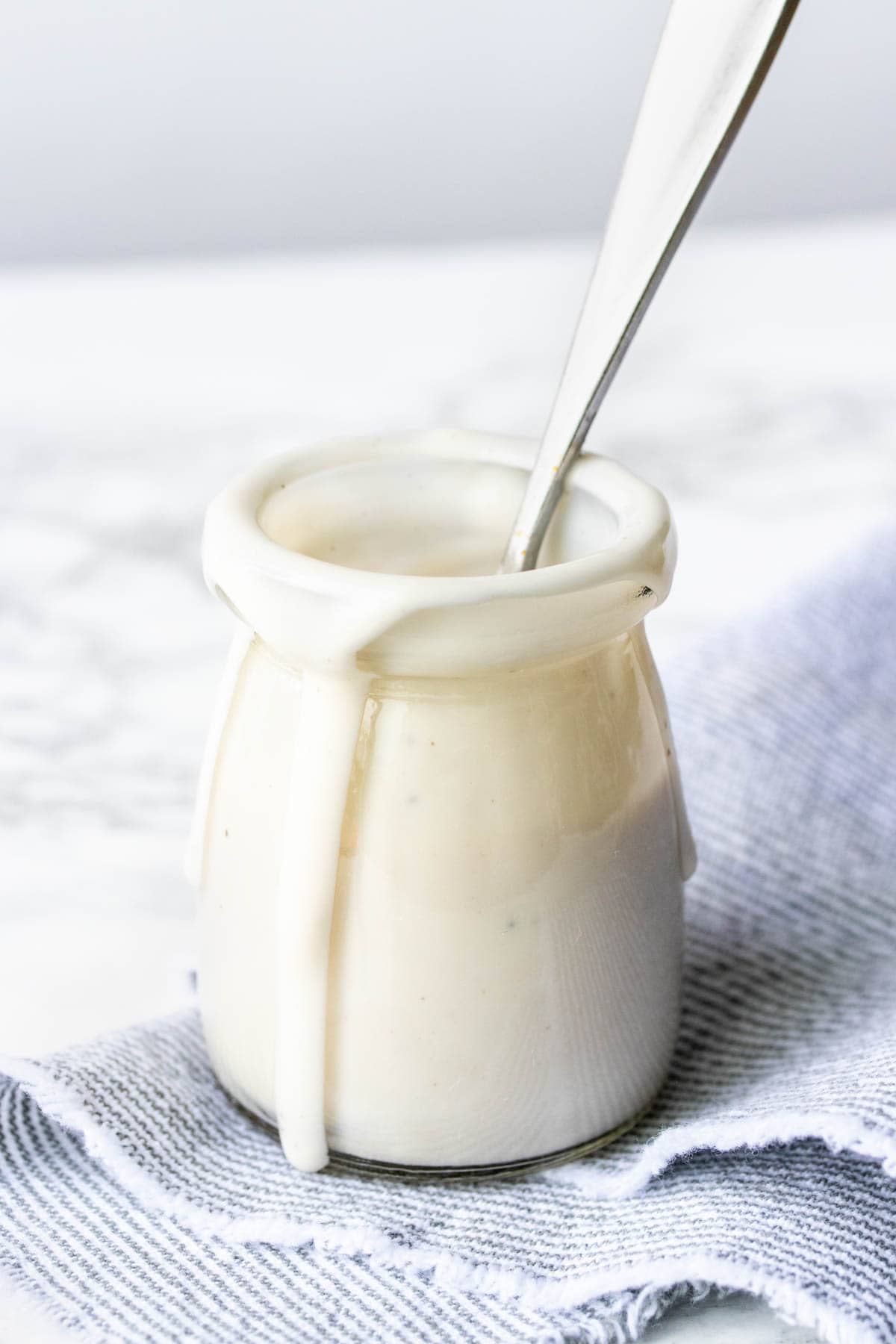 This vegan cashew cream sauce is an easy dairy sub. Add walnuts for a unique twist or stick with cashews, super customizable for any recipe! #veganrecipes #creamsauce Glass jar with walnut cashew cream sauce dripping down the side.