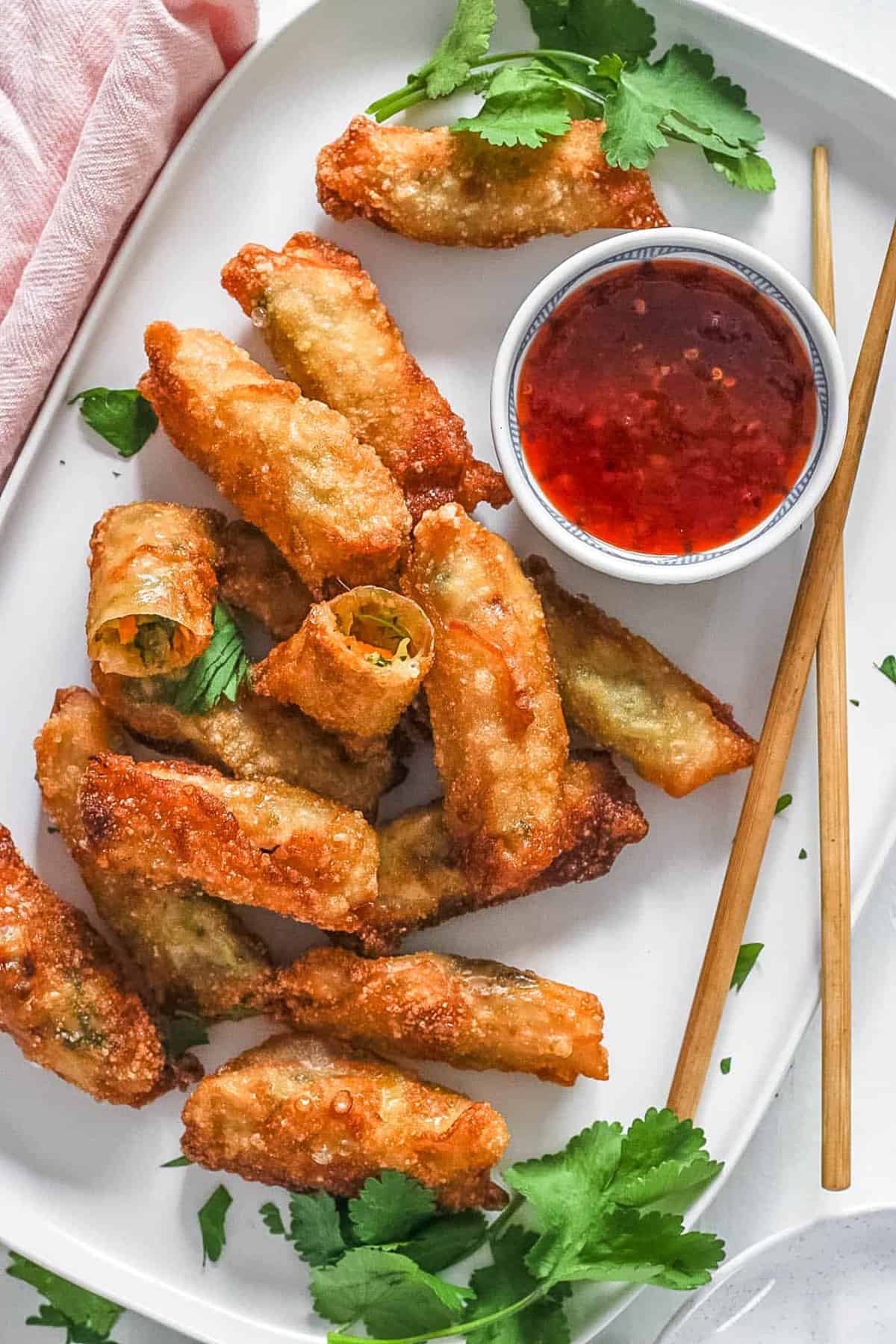 Easy vegan egg rolls served on a white plate with a dipping sauce on the side.