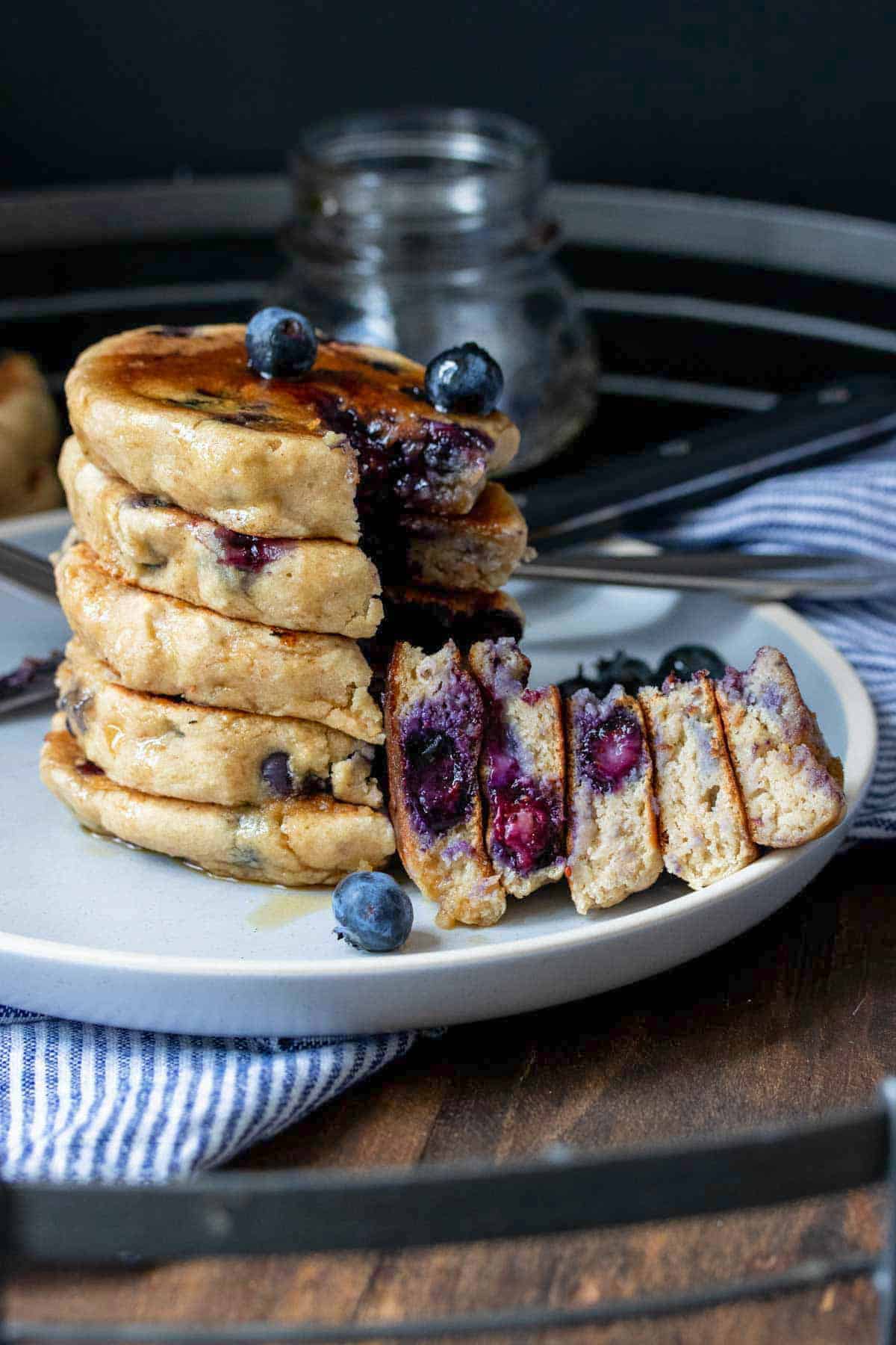 A cut out bite of vegan blueberry pancakes from a stack of them.