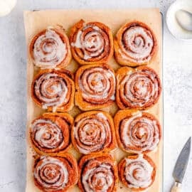 Healthy cinnamon rolls with low sugar icing, served on a large sheet of parchment paper.