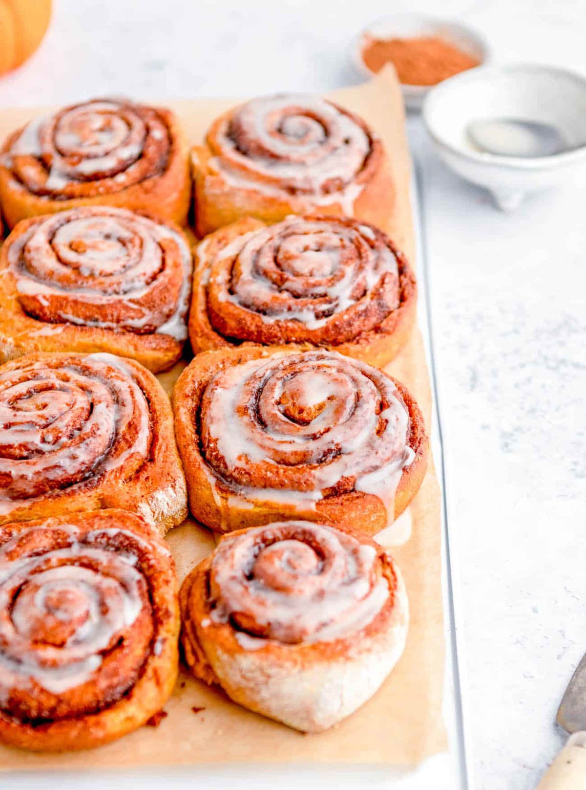 Healthy cinnamon rolls with low sugar icing, served on a piece of parchment paper.