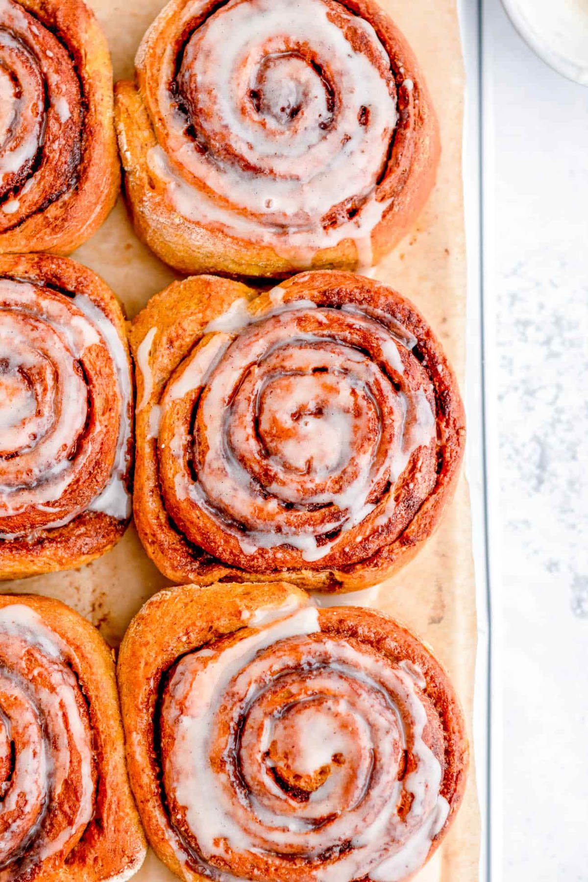 Healthy low calorie cinnamon rolls with low sugar icing, served on a large sheet of parchment paper.