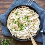 Vegan fettuccine Alfredo served in a black bowl.