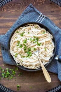 Vegan fettuccine Alfredo served in a black bowl.