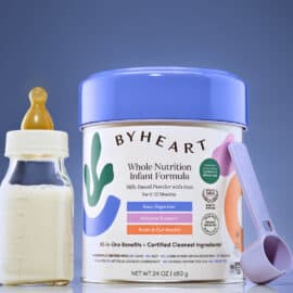 ByHeart infant formula can on a blue background with a bottle and scoop next to it.