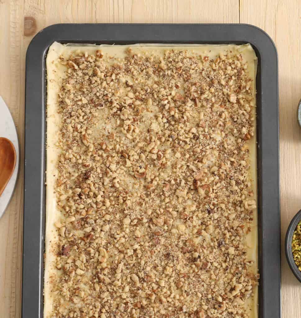 Baking sheet with phyllo dough and nuts sprinkled on top.