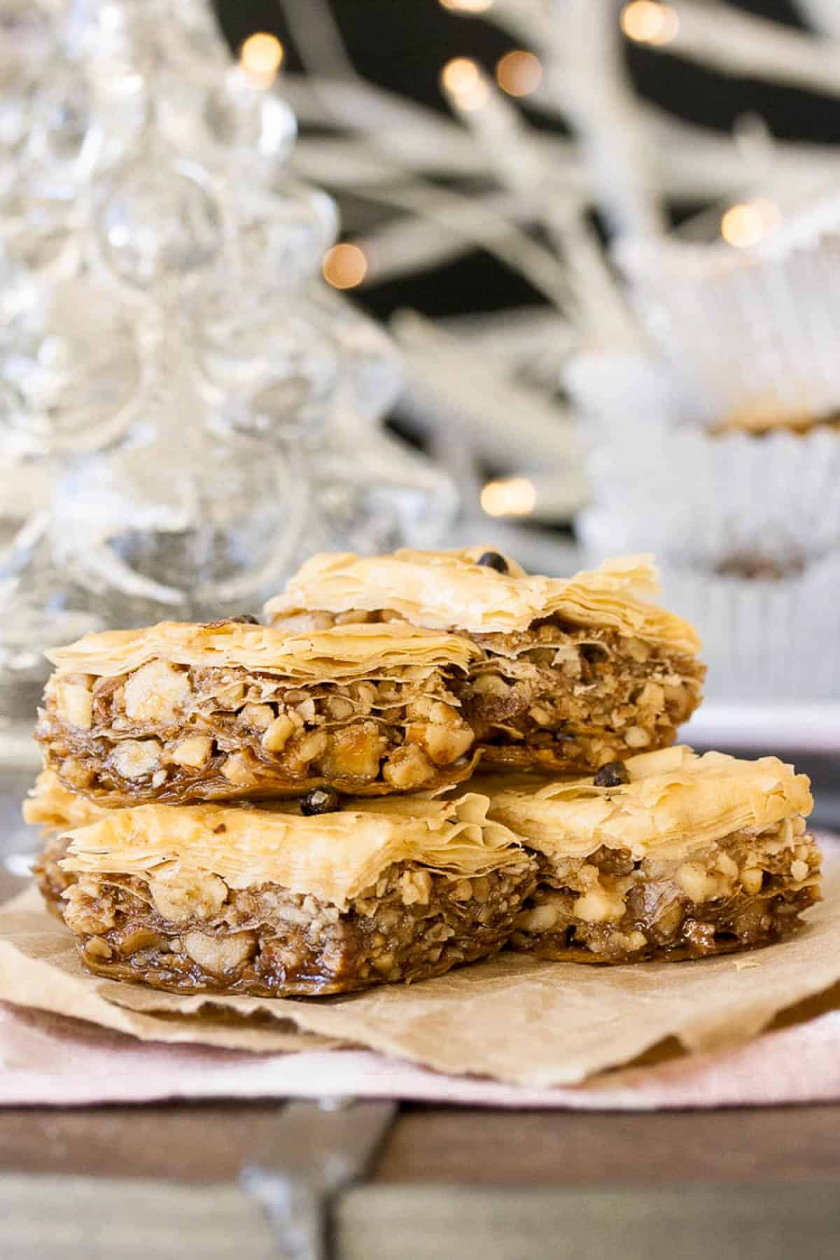 Healthy baklava stacked on a sheet of parchment paper on a table.