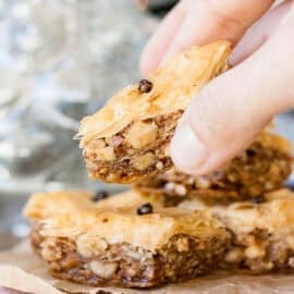 Vegan baklava being held up by a woman's hand.