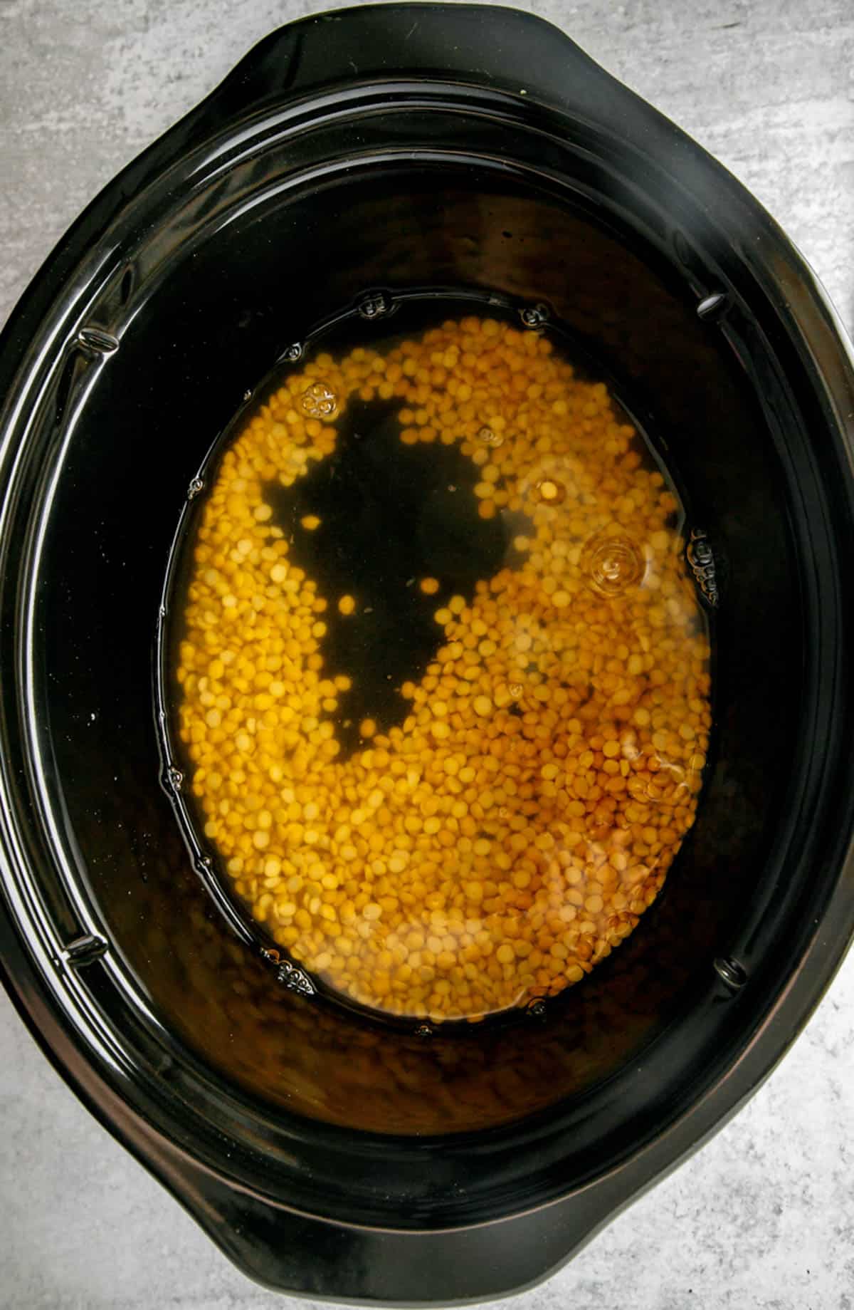 Chana dal and water added to a crock ،.