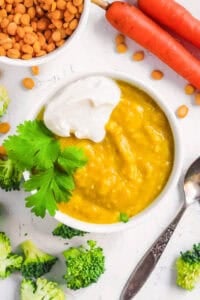 Lentils for baby served in a white bowl with some fresh herbs and veggies on the side.