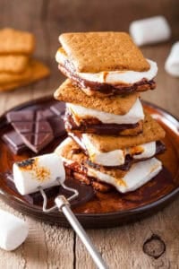 Vegan s'mores stacked on top of a wooden cutting board.