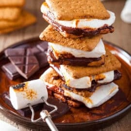 Vegan s'mores stacked on top of a wooden cutting board.