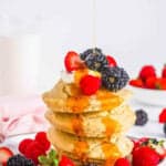 Easy air fryer pancakes topped with fresh berries and maple syrup, served on a white plate.