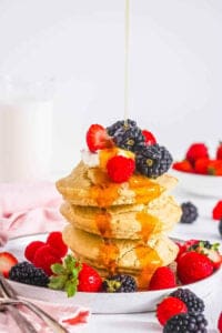 Easy air fryer pancakes topped with fresh berries and maple syrup, served on a white plate.