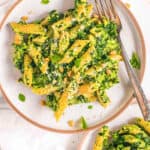 Vegetarian pesto pasta recipe with spinach, basil and pine nuts on a white plate.