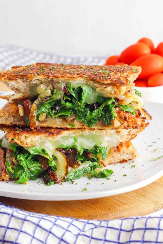 Veggie panini with kale and caramelized onion served on a white plate.