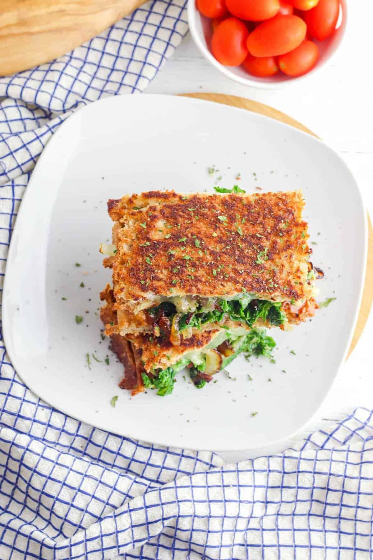 Veggie panini with kale and caramelized onion served on a white plate.