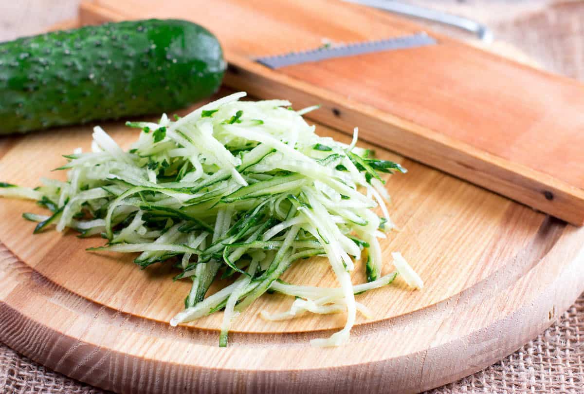 Green cucumber grated on wooden board.