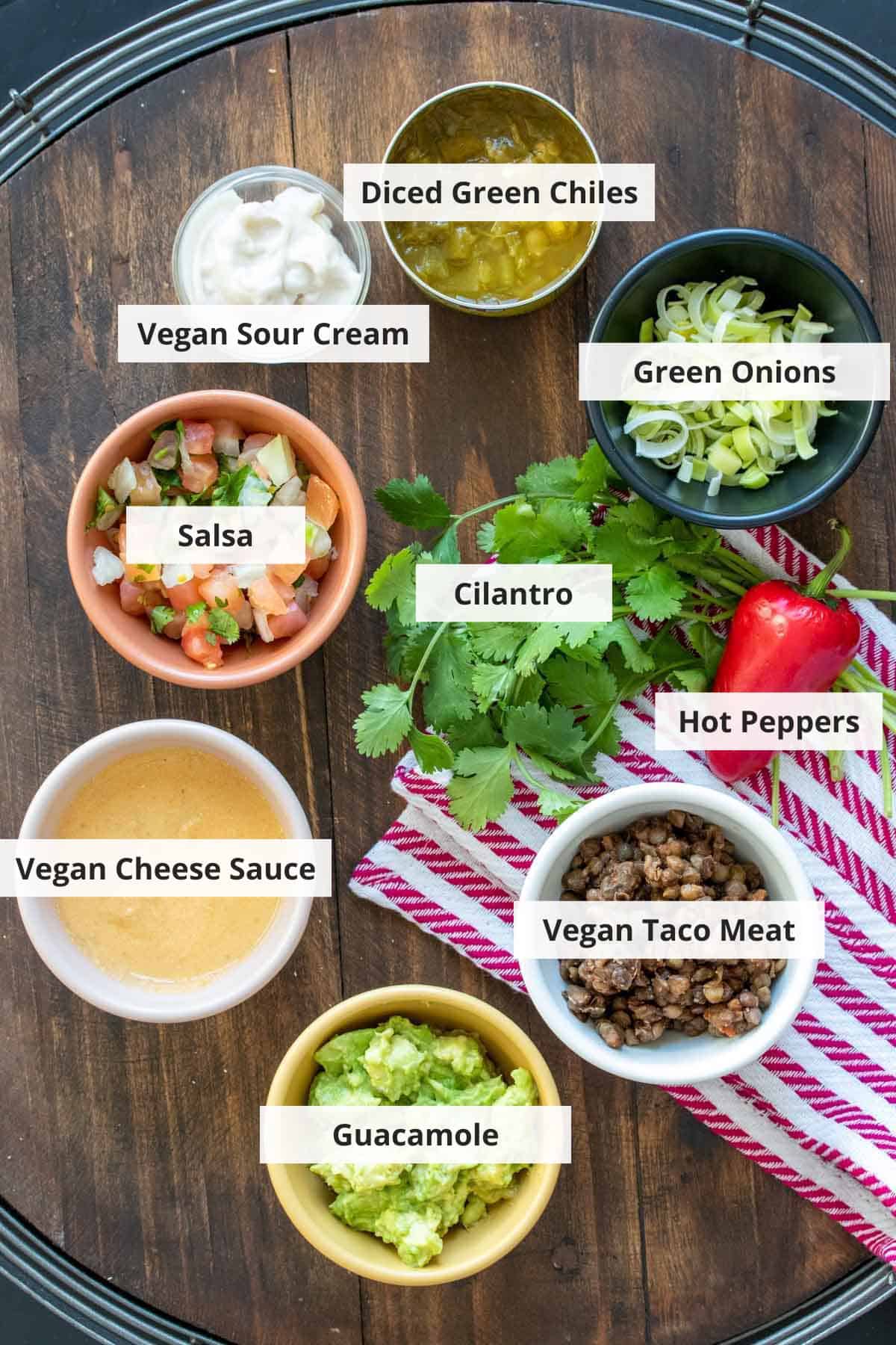 Ingredients for vegan 7 layer dip on a wood background.