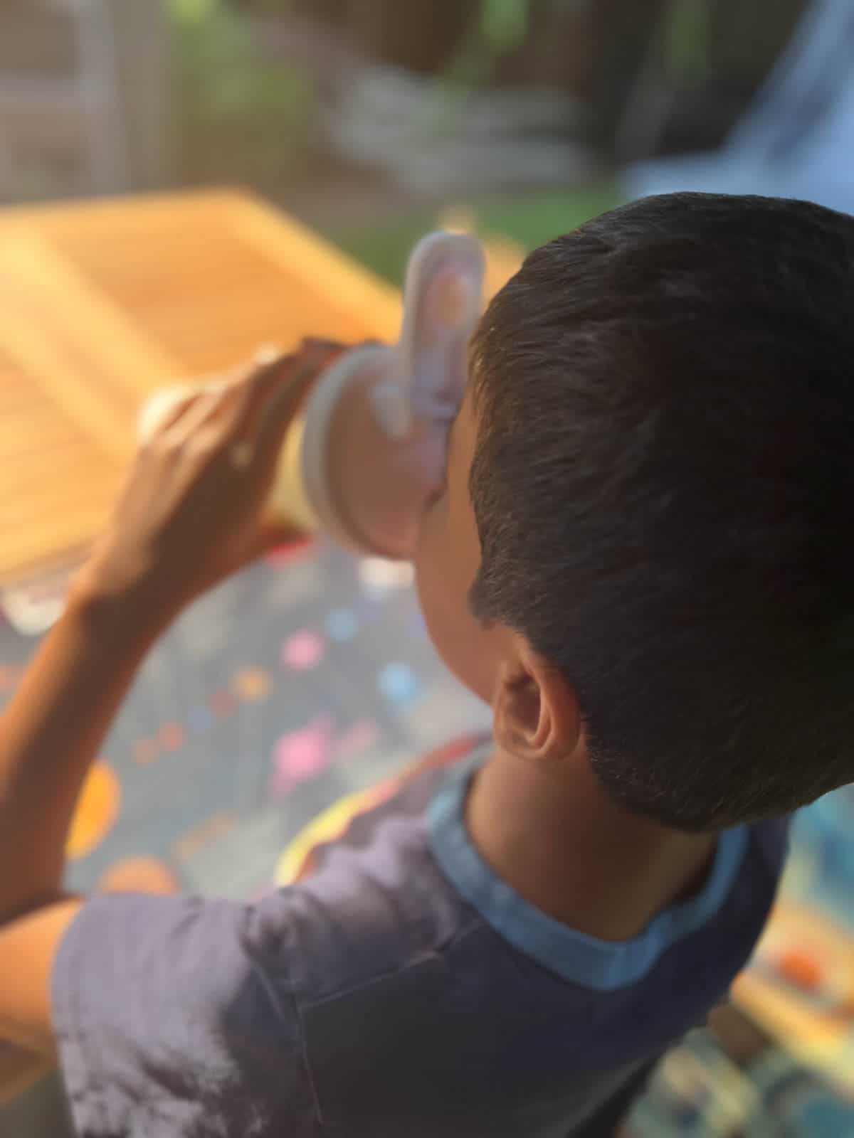 Young boy drinking Hiya greens from a shaker bottle.