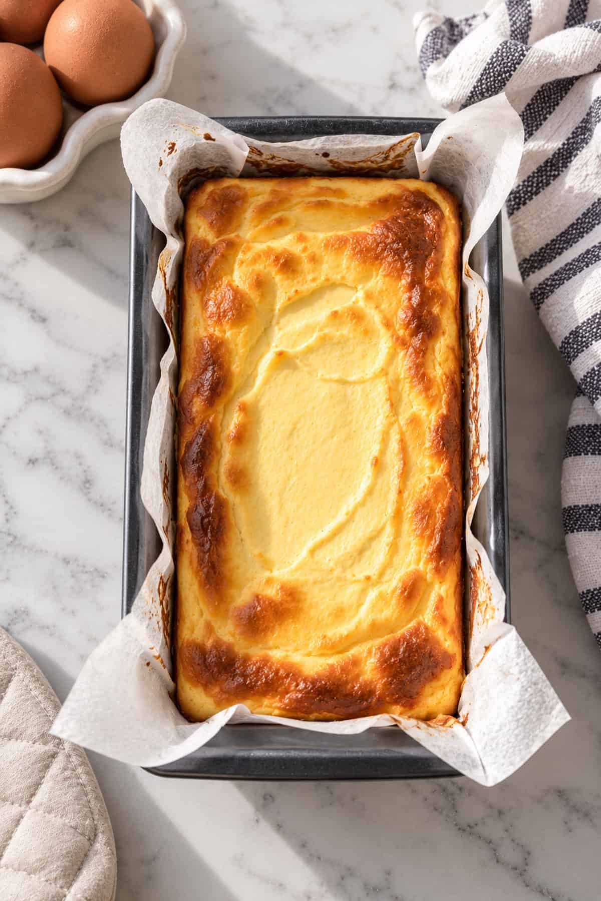 Baked cheesecake fresh out of the oven, still in the loaf pan.