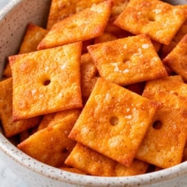 Healthy homemade cheez-its in a white ceramic bowl on a white countertop.